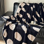 Sort-hvid plaid i fleece med prikker over sofa