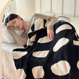Sort-hvid plaid i fleece med prikker over sofa