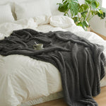 Ensfarvet minimalistisk strikket plaid draperet over sofa