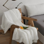 Ensfarvet minimalistisk strikket plaid draperet over sofa