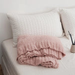 Ensfarvet minimalistisk strikket plaid draperet over sofa