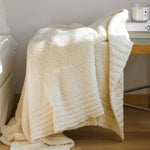 Ensfarvet minimalistisk strikket plaid draperet over sofa