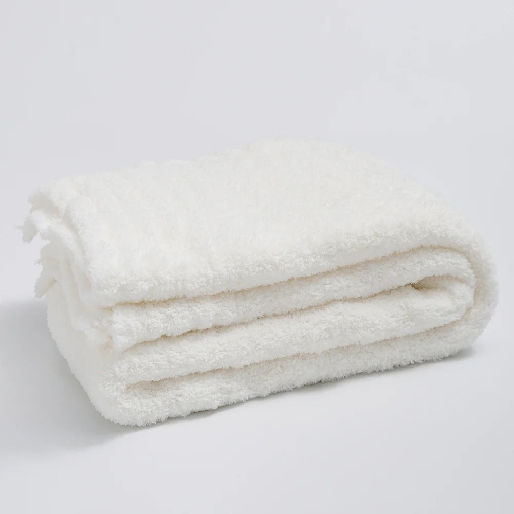 Ensfarvet minimalistisk strikket plaid draperet over sofa