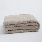 Ensfarvet minimalistisk strikket plaid draperet over sofa