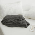 Ensfarvet minimalistisk strikket plaid draperet over sofa