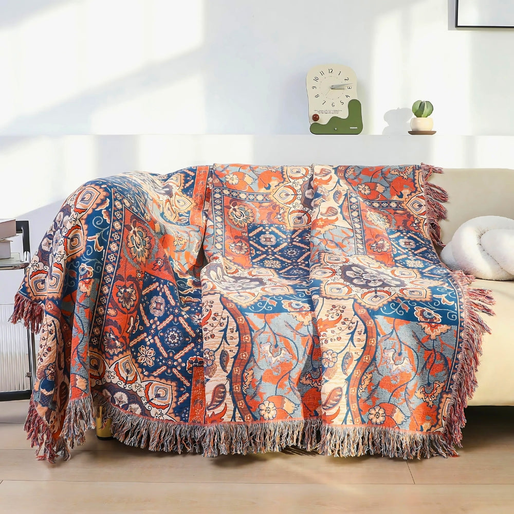 Bomuldsplaid med blomsterjacquard i orange og blå over sofaen