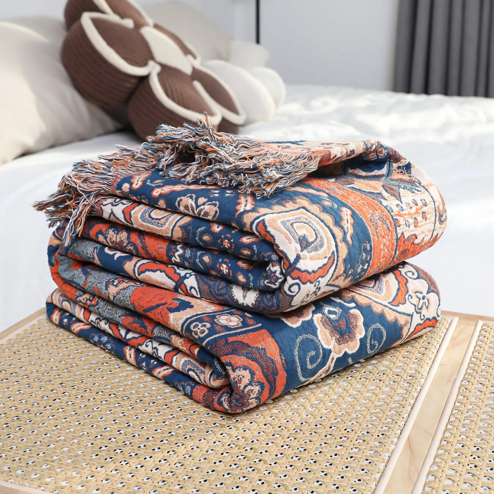 Bomuldsplaid med blomsterjacquard i orange og blå over sofaen