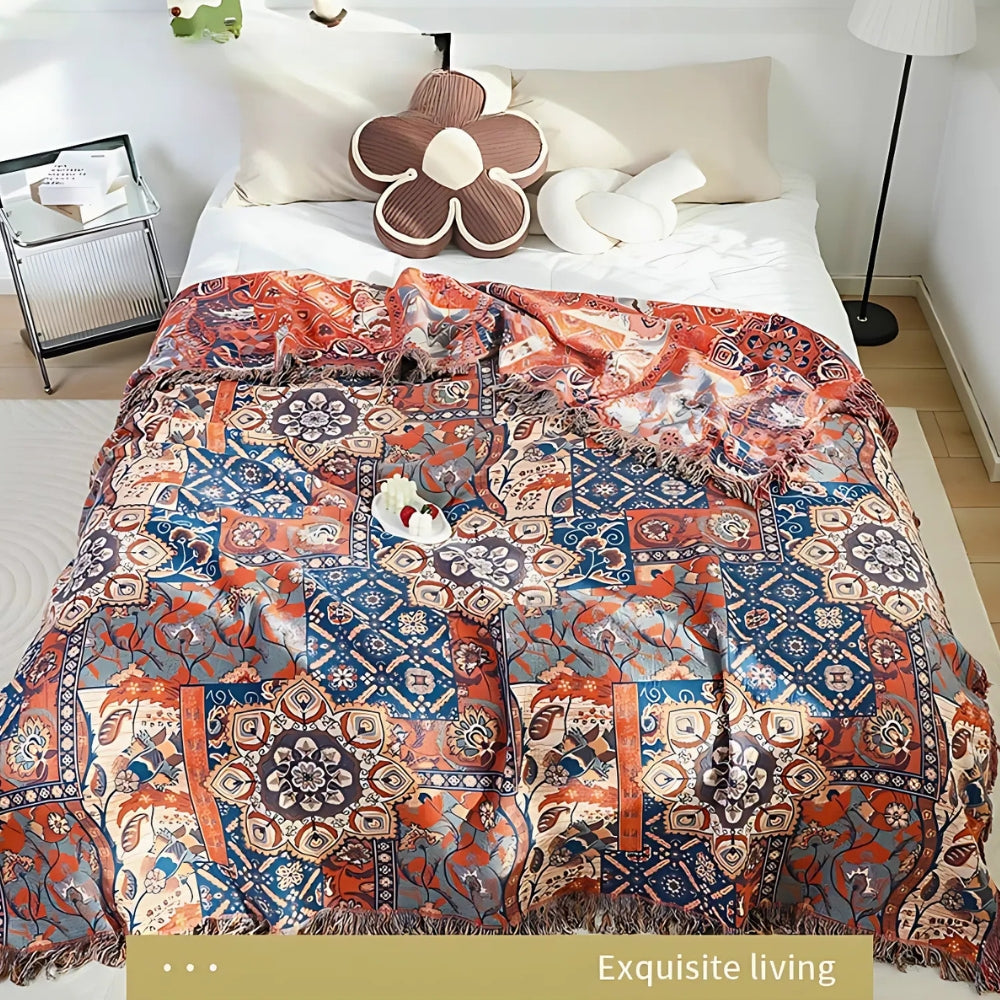 Bomuldsplaid med blomsterjacquard i orange og blå over sofaen