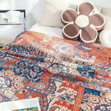 Bomuldsplaid med blomsterjacquard i orange og blå over sofaen