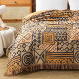 Vendbart bomuldstæppe med tribal-patchwork og kvaster over sofa