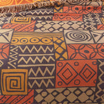 Vendbart bomuldstæppe med tribal-patchwork og kvaster over sofa