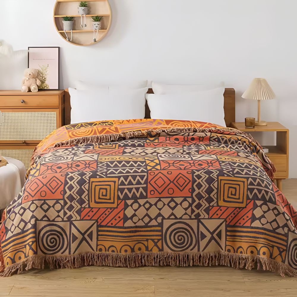 Vendbart bomuldstæppe med tribal-patchwork og kvaster over sofa