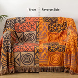 Vendbart bomuldstæppe med tribal-patchwork og kvaster over sofa