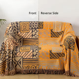 Vendbart bomuldstæppe med tribal-patchwork og kvaster over sofa