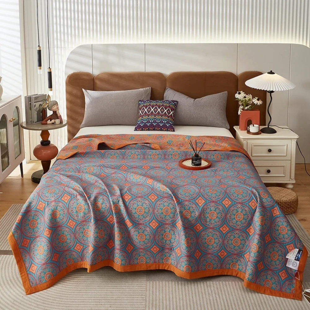 Vendbart sommertæppe i bomuld med ginkgobladsdesign over en seng