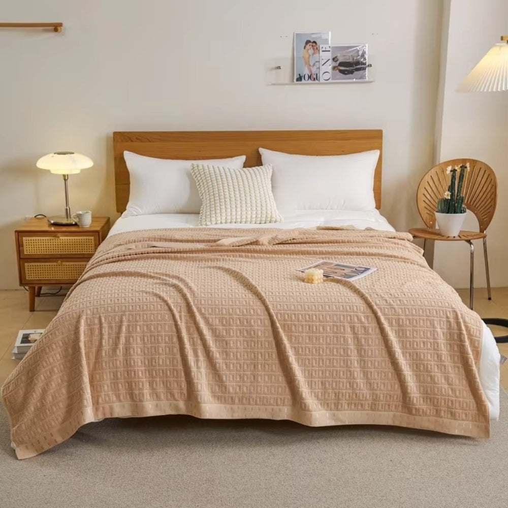 Vaffelvævet bomuldstæppe i beige draperet over sofa