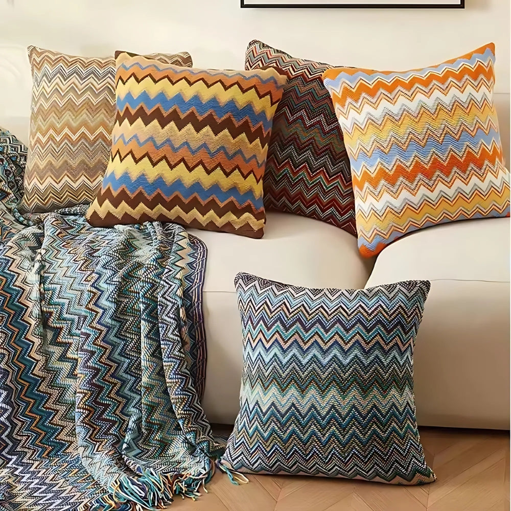 Strikket boho pudebetræk med zigzagstriber i varme toner på sofa