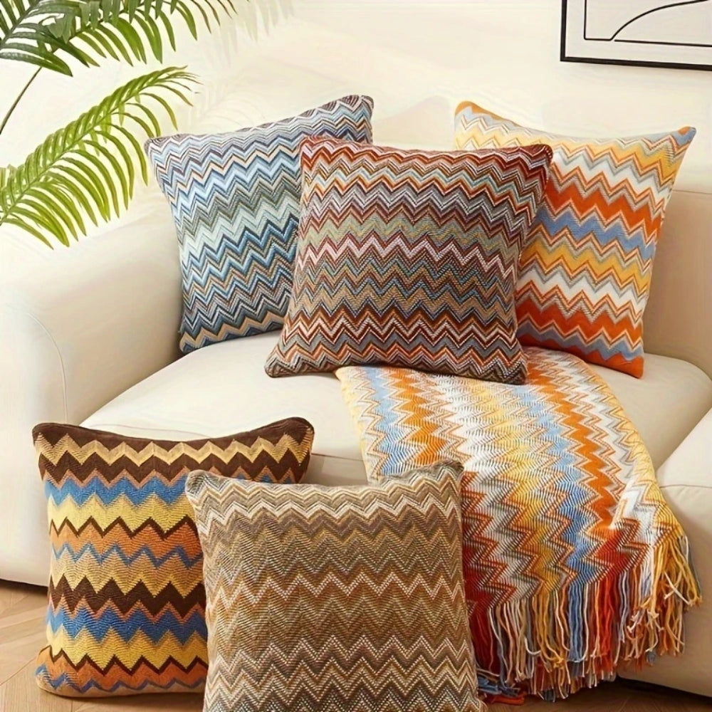 Strikket boho pudebetræk med zigzagstriber i varme toner på sofa